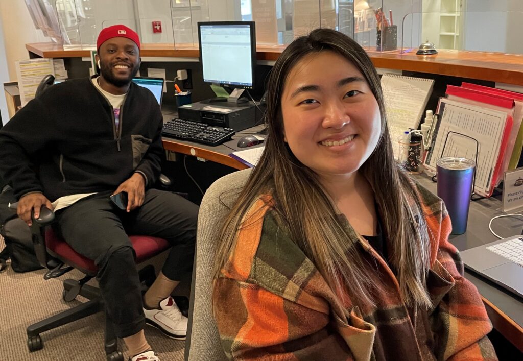 Two students working at the library information desk