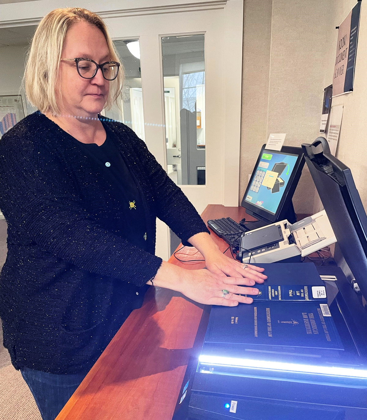 A library staff member scans pages from a book.